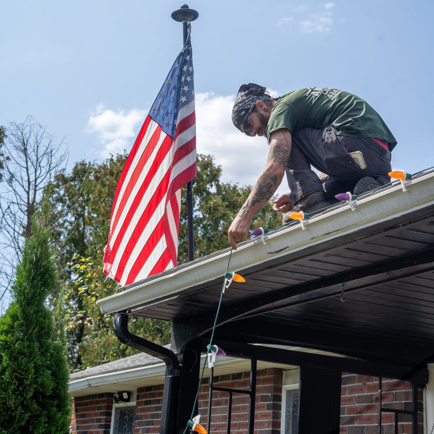 Anderson Lawn Care crew member working beside an American flag